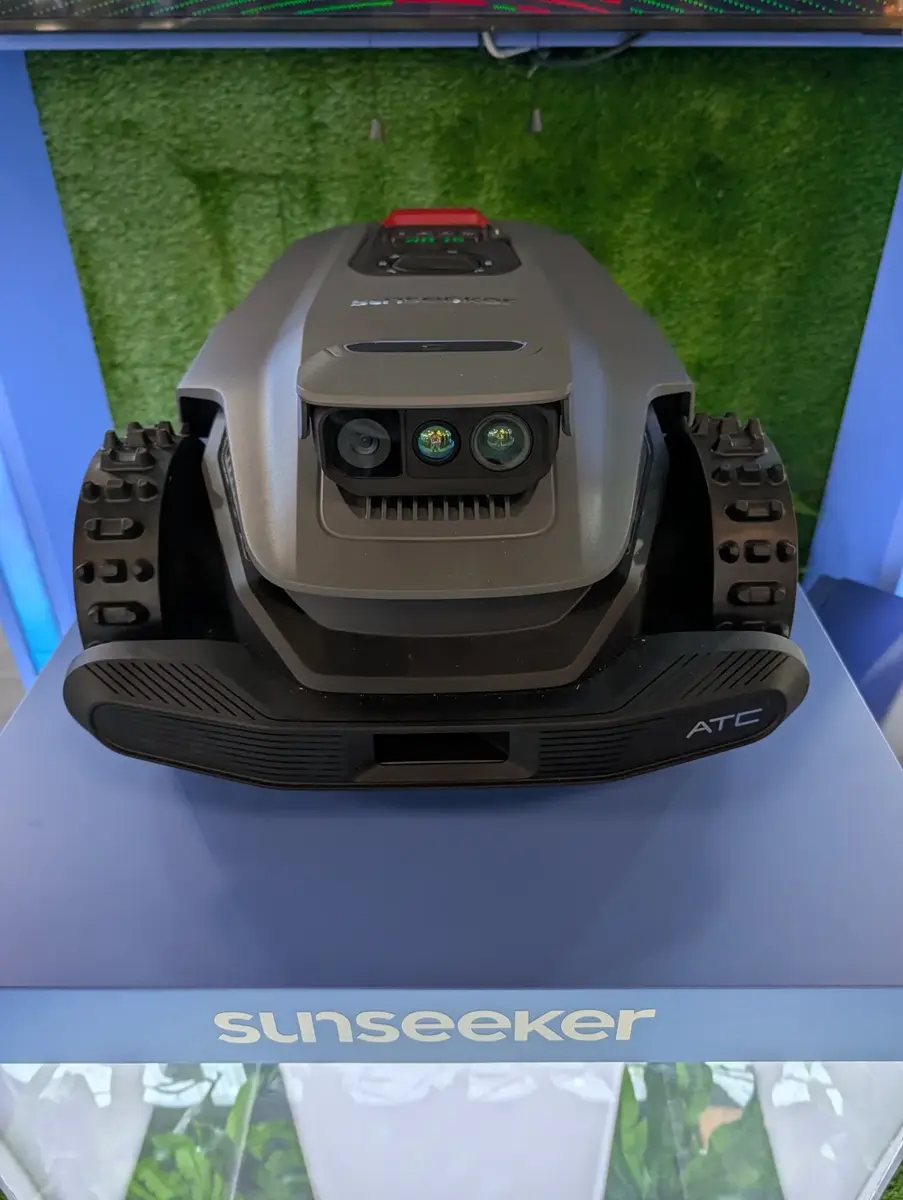 Frontansicht des Sunseeker S7 LiDAR Ultra AWD auf einem Podest: grauer Körper mit rotem Stoppknopf, vorn ein Sensormodul mit einer Weitwinkelkamera und zwei weiteren Linsen, grobstollige Räder, unten am Stoßfänger die Aufschrift ATC.